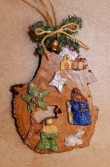 Painted wood ornament of two shepherds with a sheep, a nearby palm tree, the Star, and in the distance the little town of Bethlehem & a tiny gold-colored bell and cord at the top.